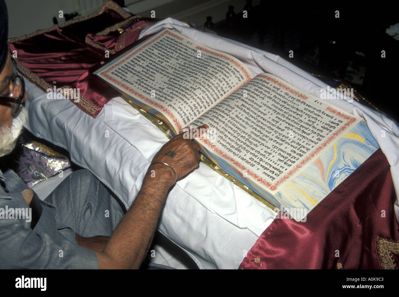 Il Granthi scegliendo un nuovo nome del bambino dal Guru Granth Sahib o sacri testi Sikh Foto Stock