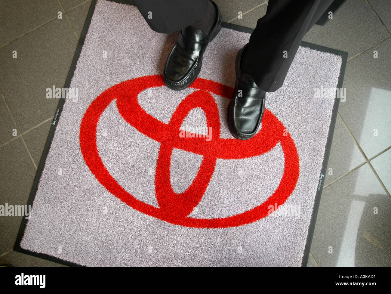 Un clienti piedi appoggiati sul logo di una Toyota tappetino sul pavimento di una sala di esposizione Foto Stock