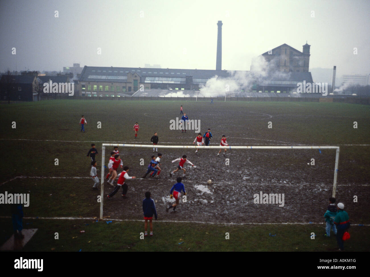 I ragazzi immigranti di origine sudasiatica giocano a calcio all'ombra di una fabbrica a Bradford West Yorkshire Inghilterra negli anni '90 Foto Stock
