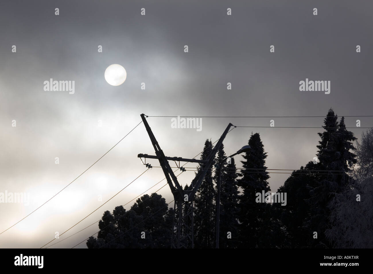 Sun dietro le nuvole grigie e linee elettriche Foto Stock