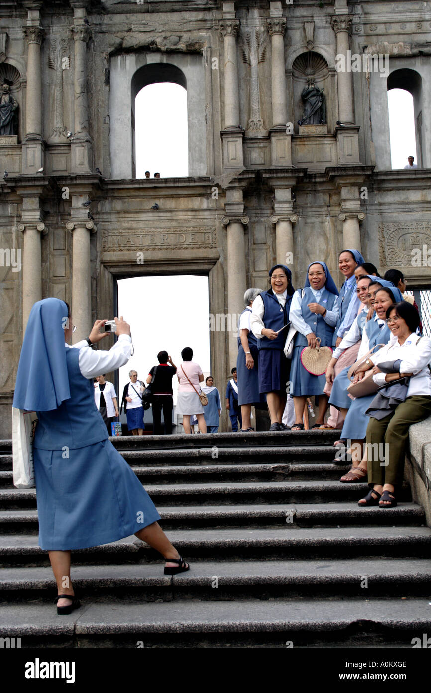 Le monache cristiani pongono per foto ricordo davanti alle rovine della chiesa di San Paolo a Macao, SAR Foto Stock