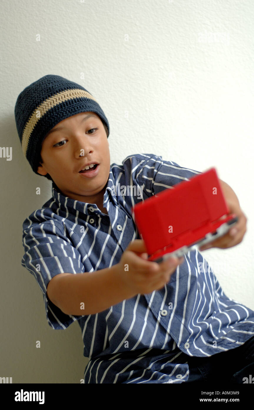 Ritratto di 9 anni vecchio ragazzo giocando con un palmare video gioco Foto Stock