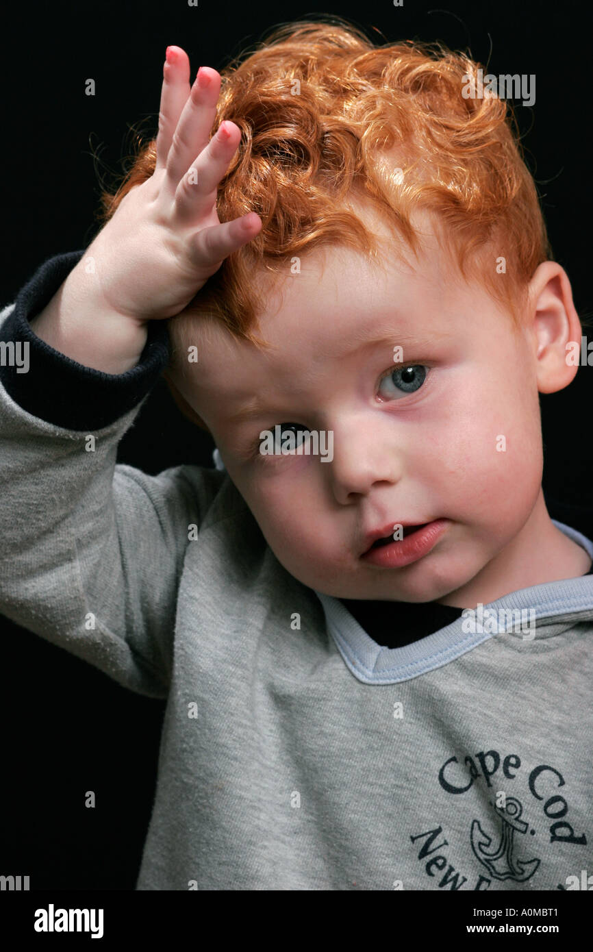 Il volto di un bambino con i capelli rossi su sfondo nero Foto stock - Alamy