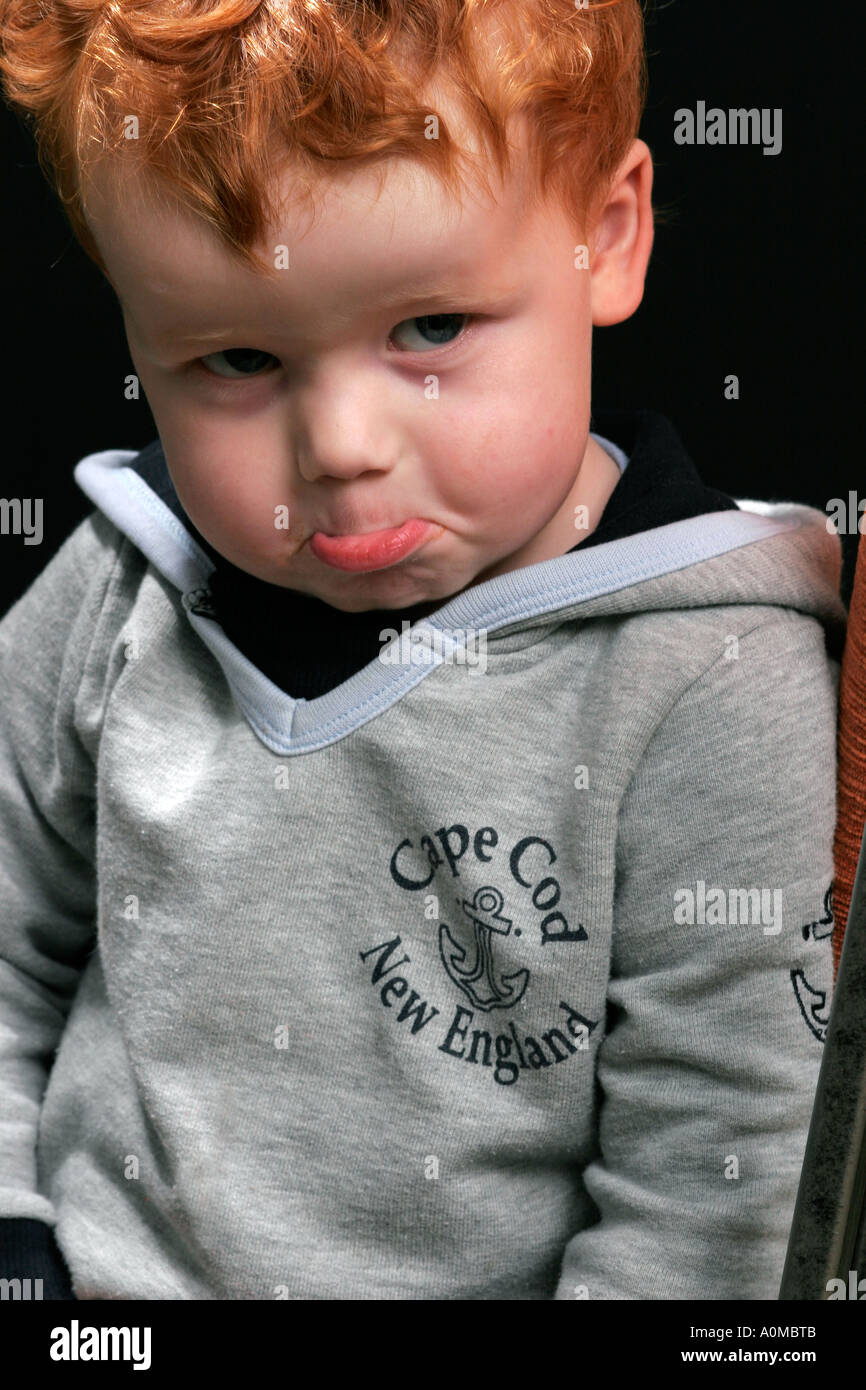 Il volto di un bambino con i capelli rossi su sfondo nero Foto stock - Alamy