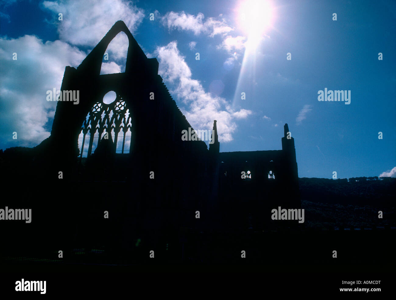 Sunburst attraverso la silhouette di Tintern Abbey, rovine , Galles del Sud Foto Stock