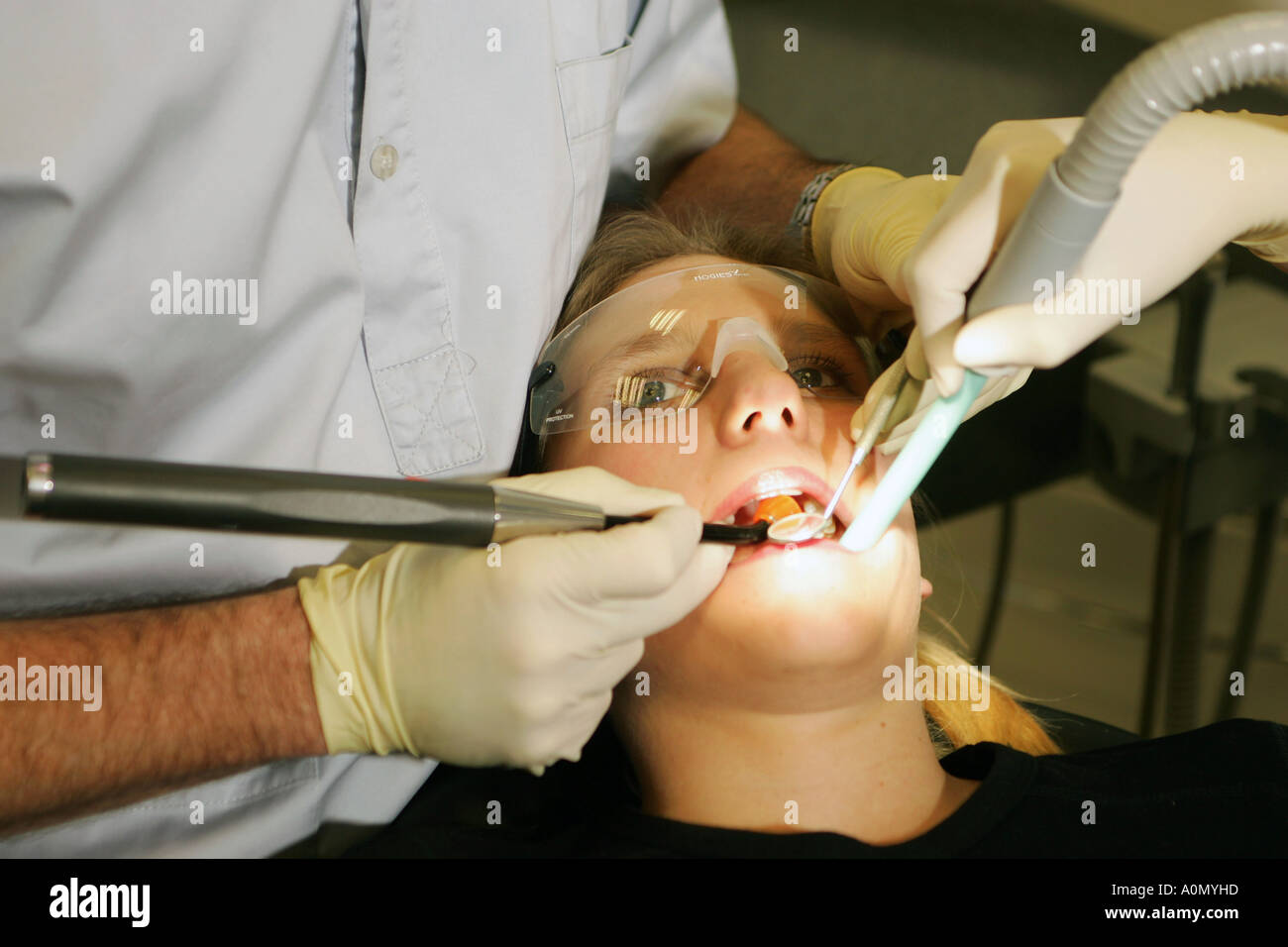 Denti e gomma di trattamento da parte di un medico dentista e il suo assistente in un paziente in una sedia dentisti in una chirurgia dentale Foto Stock