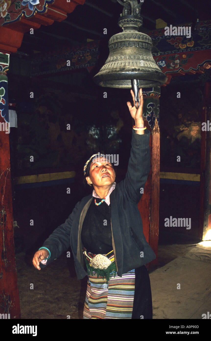 Donna buddista squilla una campana appesa in un monastero a guadagnare il merito ,Tibet.La Cina Foto Stock