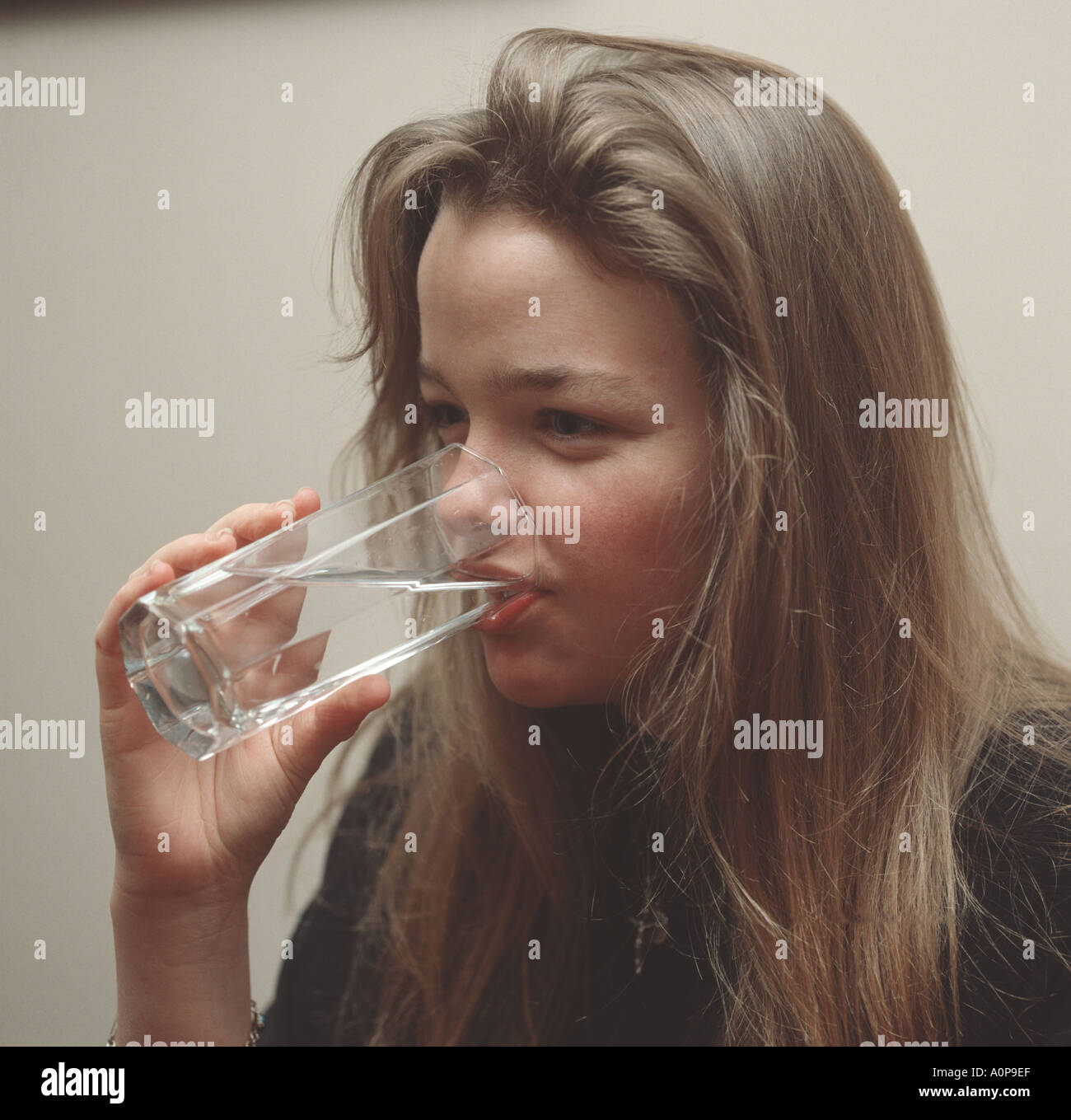 Ragazza europea acqua potabile da un vetro trasparente Foto Stock