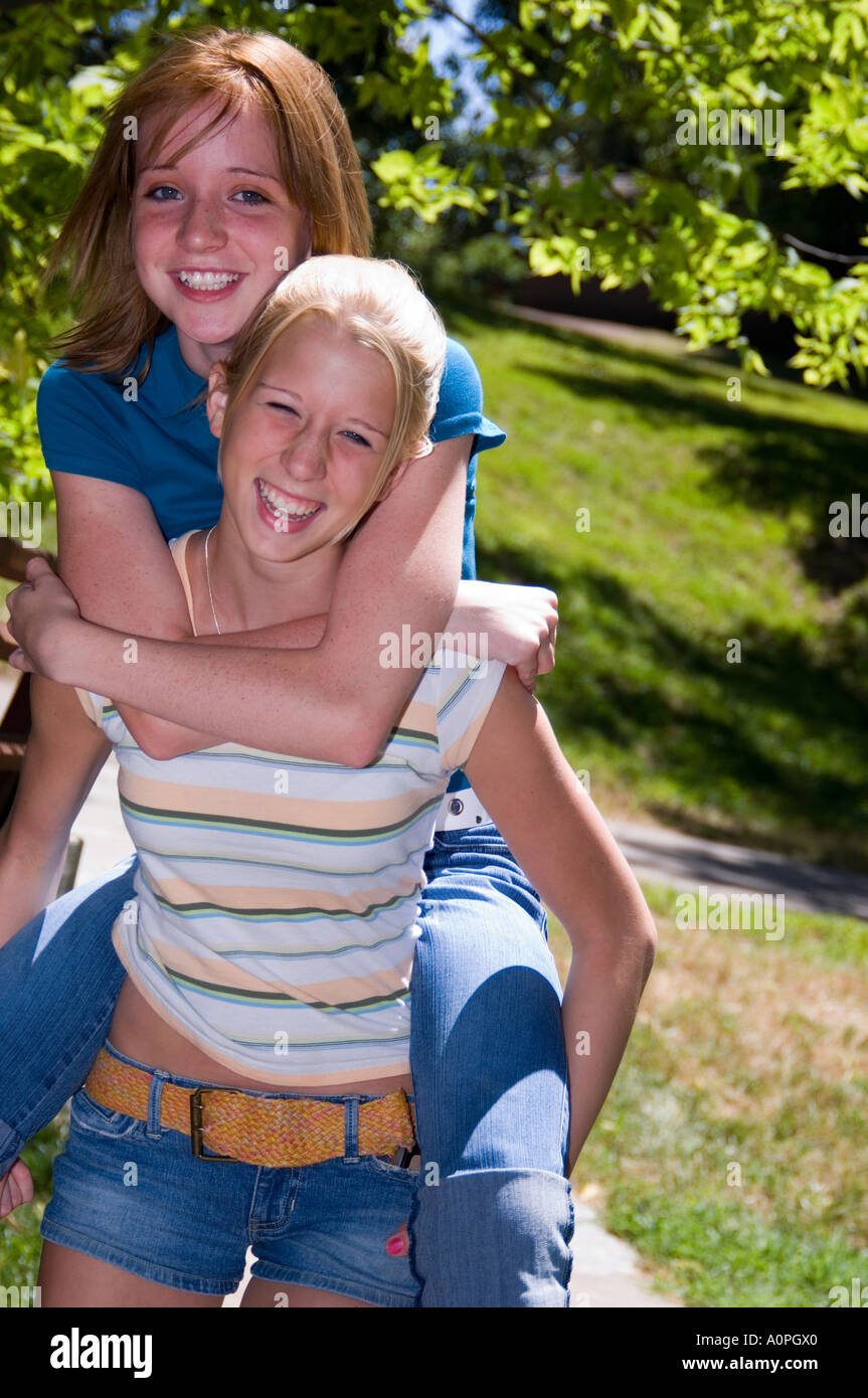 Due giovani ragazze, uno fornendo un piggyback ride per gli altri Foto Stock
