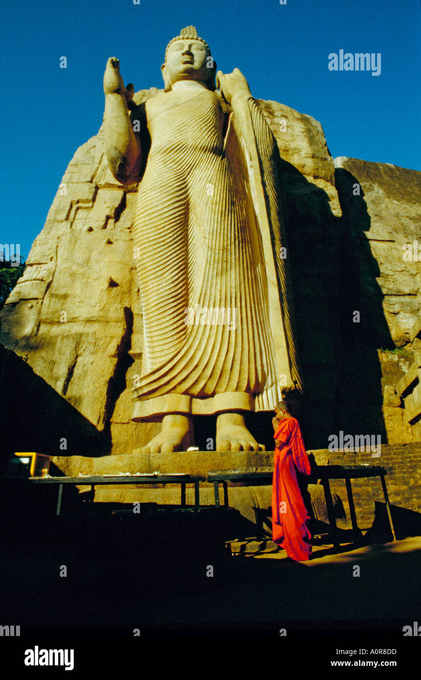 Un monaco offre tempio fiori e preghiere al Buddha Aukana un 40ft statua scolpita 1 500 anni fa da una giungla rockface Foto Stock