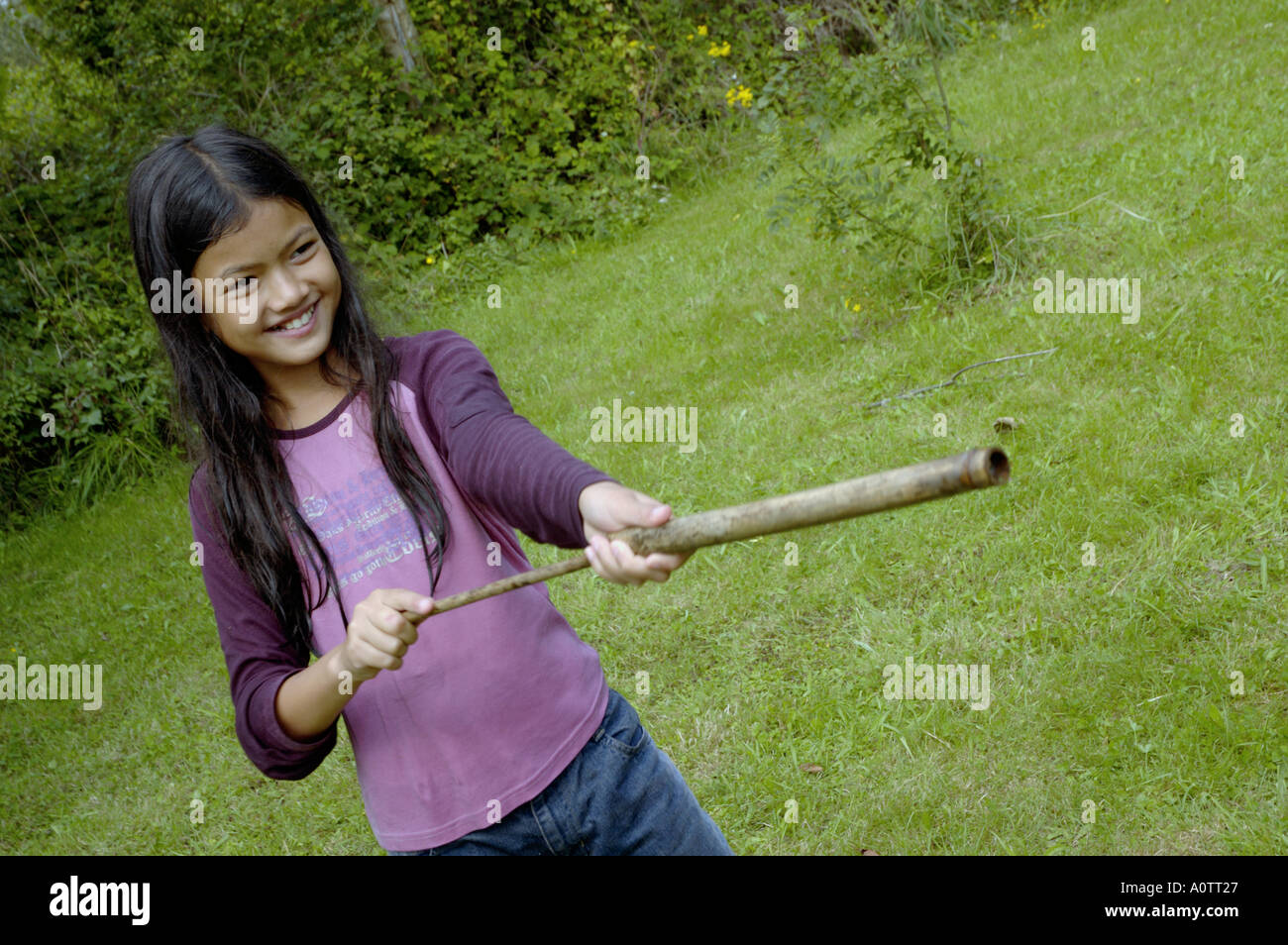 Ragazza giovane giocando con bambù pistole per acqua Foto Stock