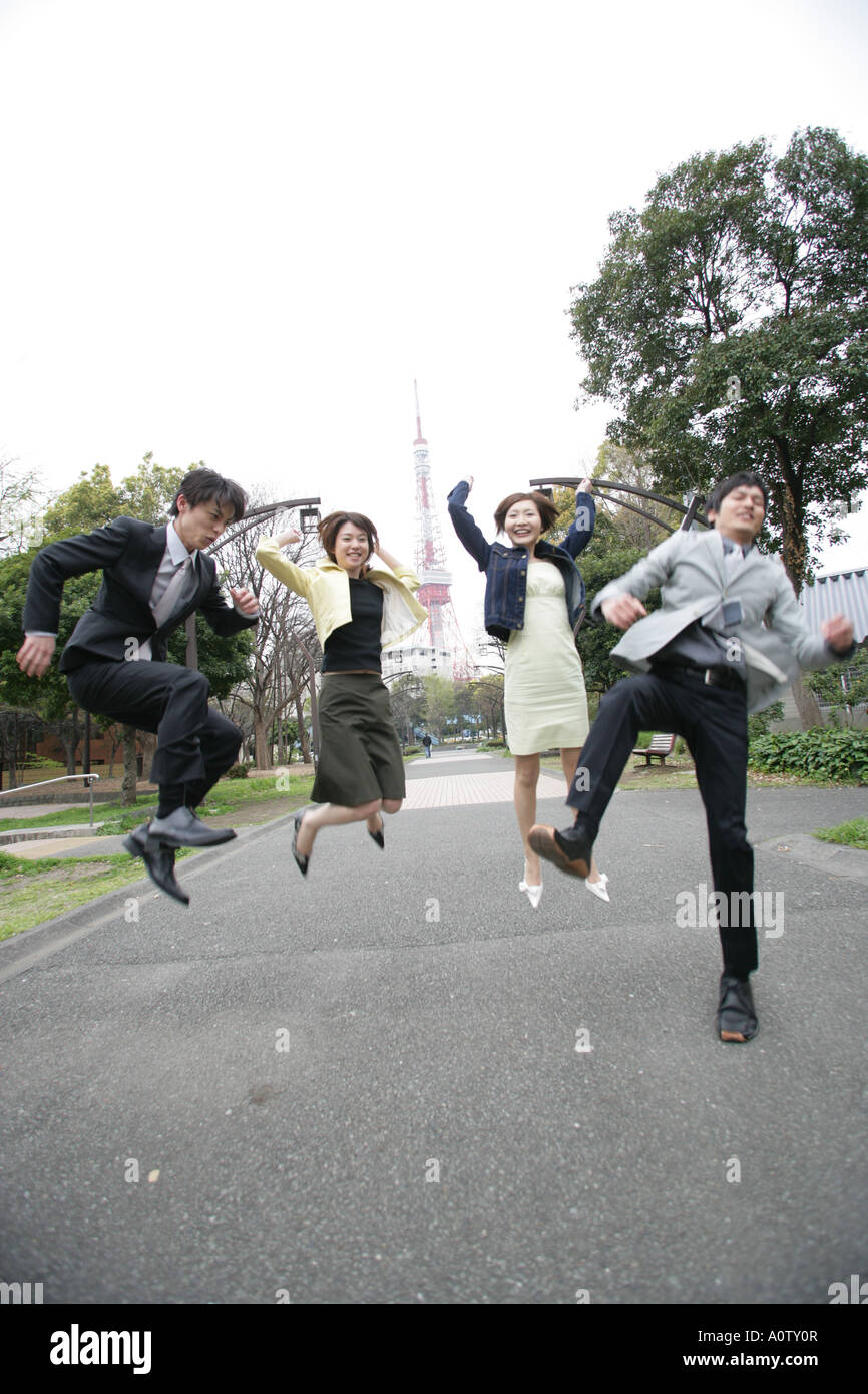 Due imprenditori e due imprenditrici jumping in un parco Foto Stock