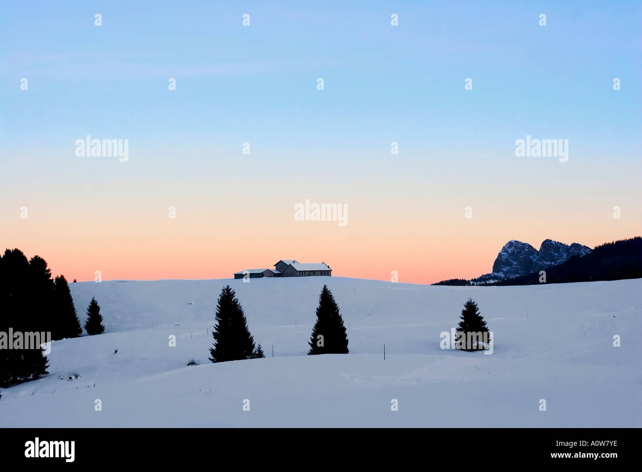 Panorarama paesaggio paesaggio di montagna con la neve e il tramonto rosso e blu cielo con piccola fattoria Foto Stock
