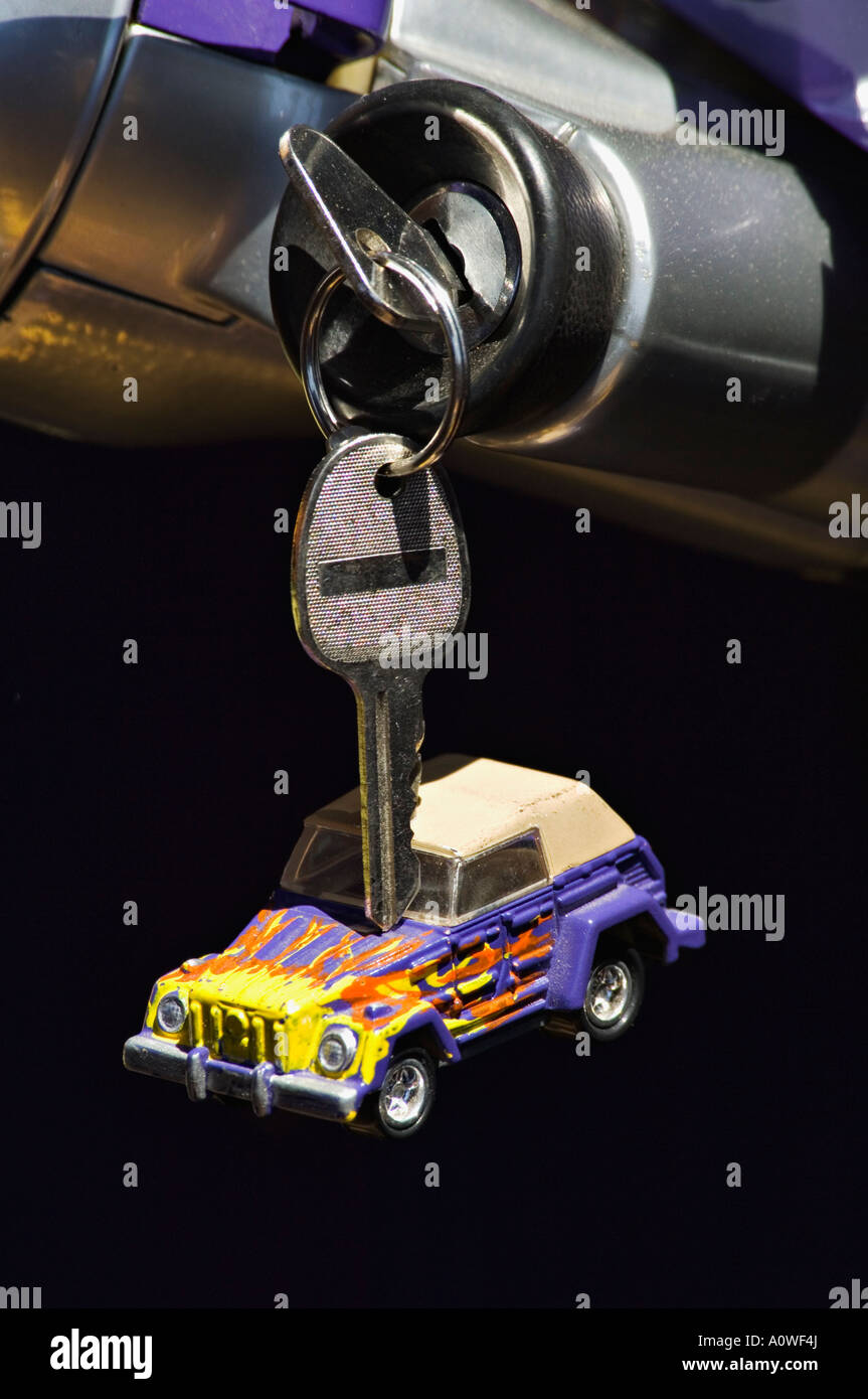 La chiave nel commutatore di accensione della Volkswagen cosa con replica giocattolo del veicolo appeso al portachiavi Foto Stock