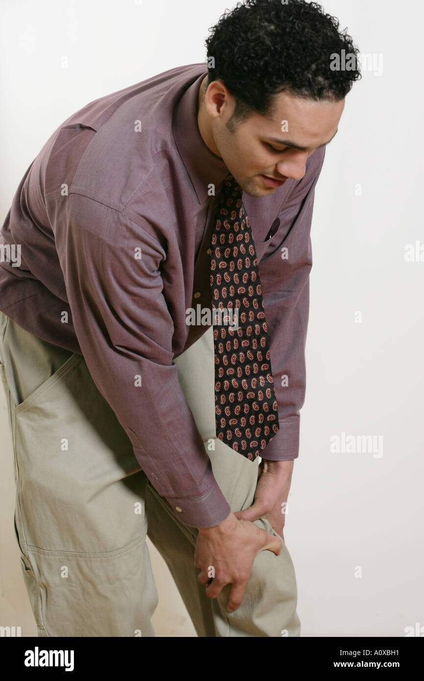 Uomo con il dolore al ginocchio tiene il suo ginocchio nel dolore. Foto Stock