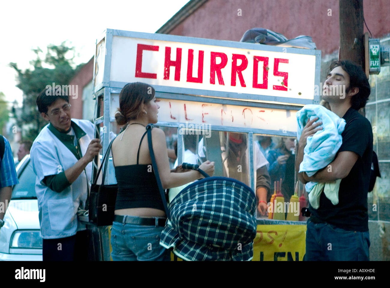 Giovane comfort il loro bambino da un alimento bancarella vendendo churros in Coyoacan Città Del Messico Foto Stock