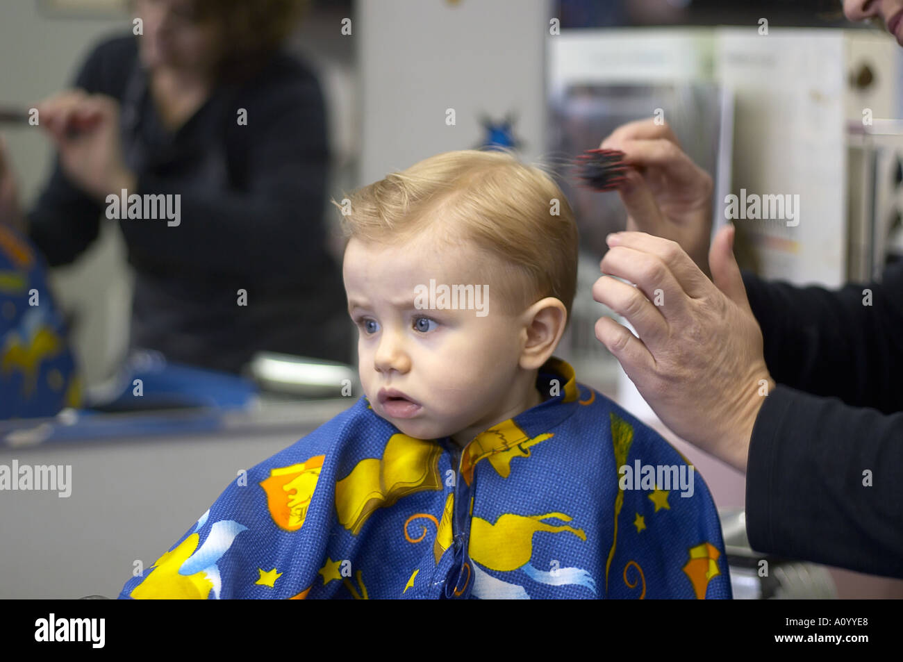 Un anno vecchio ragazzo si siede nel barbiere sgabello per il primo taglio  di capelli toddler