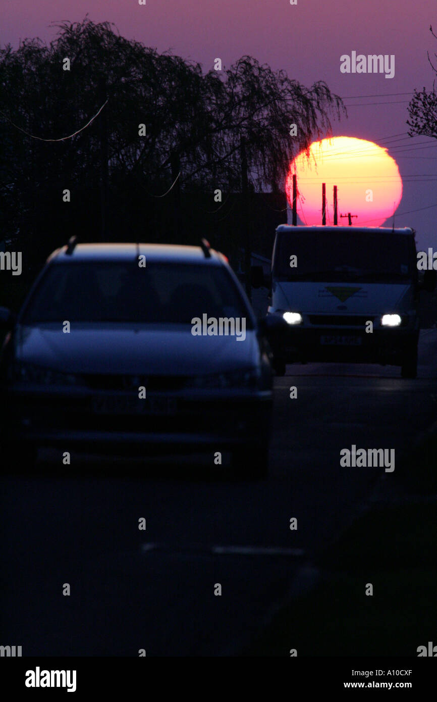 Un tramonto dietro un auto Foto Stock