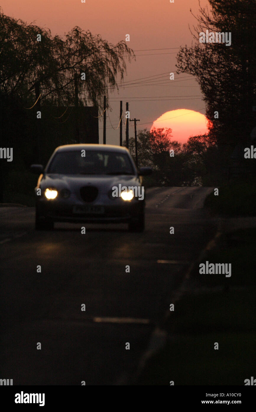 Un tramonto dietro un auto Foto Stock