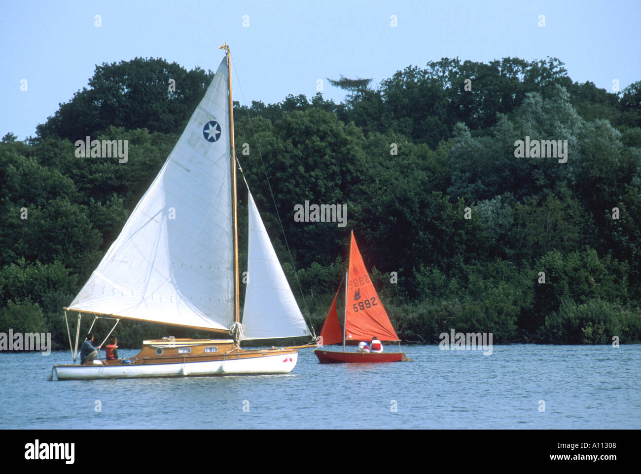 Due barche a vela sotto la vela, crociera lungo il fiume e gommoni, wroxham ampia, norfolk, East Anglia England Regno Unito Foto Stock