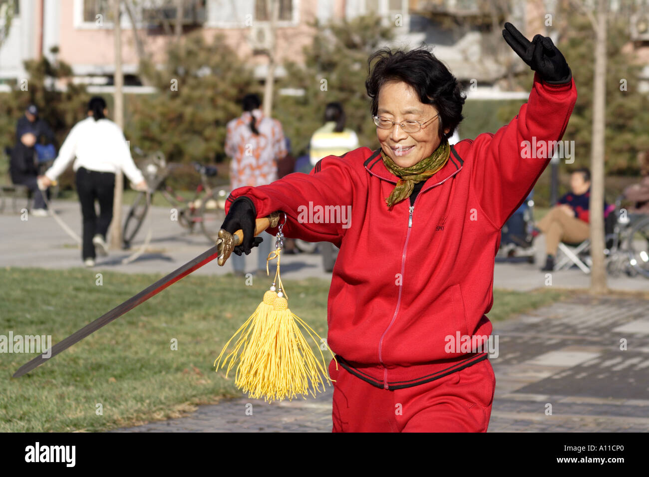 Senior Citizen balzi in avanti con la sua spada in un parco lungo Yinshui Qu, Hucheng fiume (il fossato della città), Pechino, Cina Foto Stock