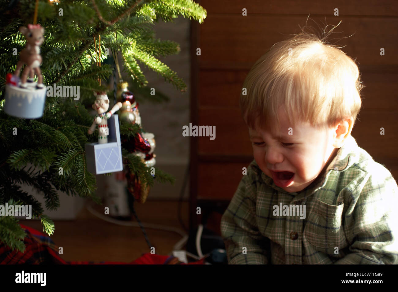 Happy baby boy toddler giocando con ornamento di Natale vicino albero di natale Foto Stock