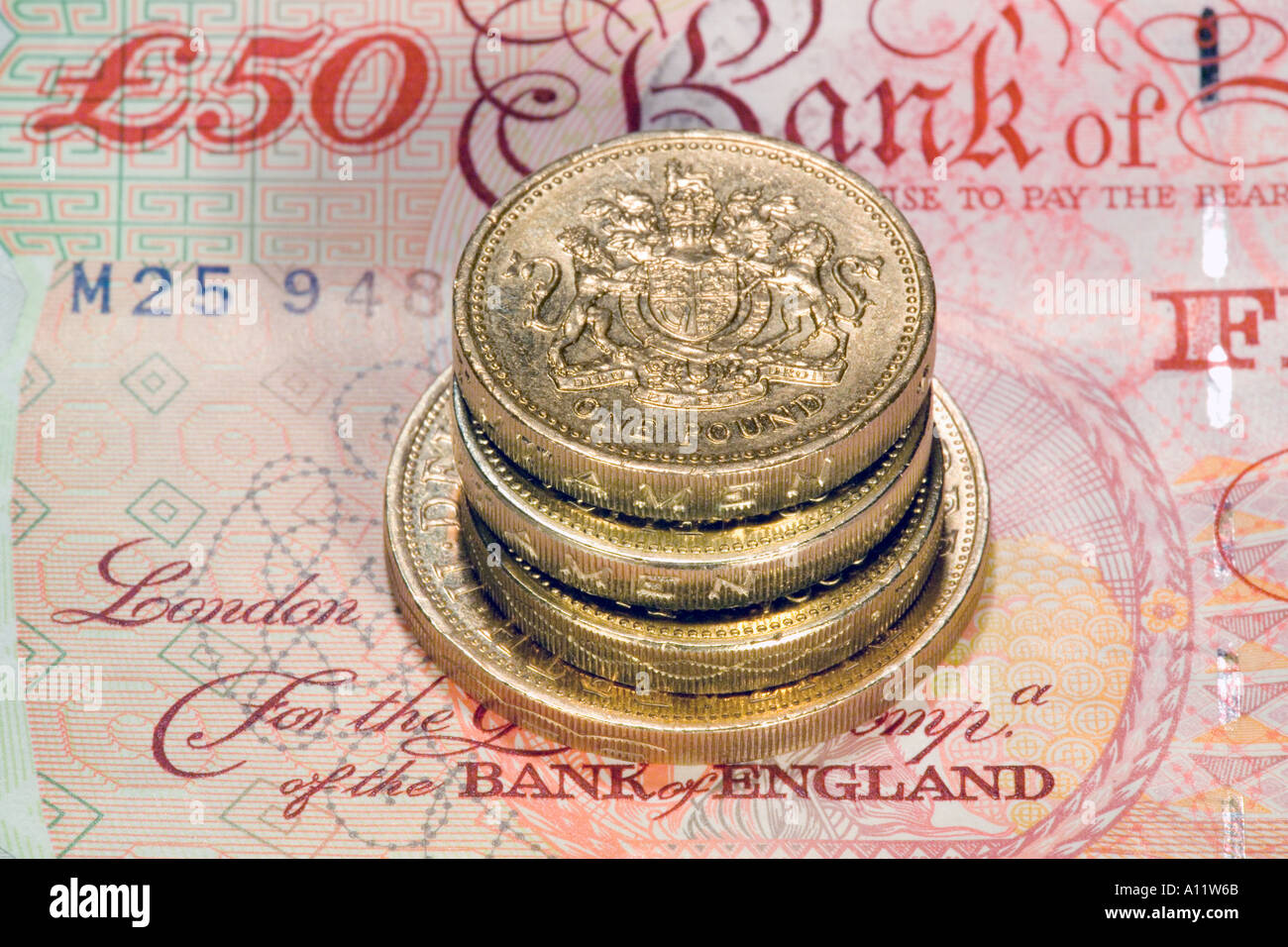 Pila di 1 una sterlina britannica monete su 50 nota banca Foto Stock
