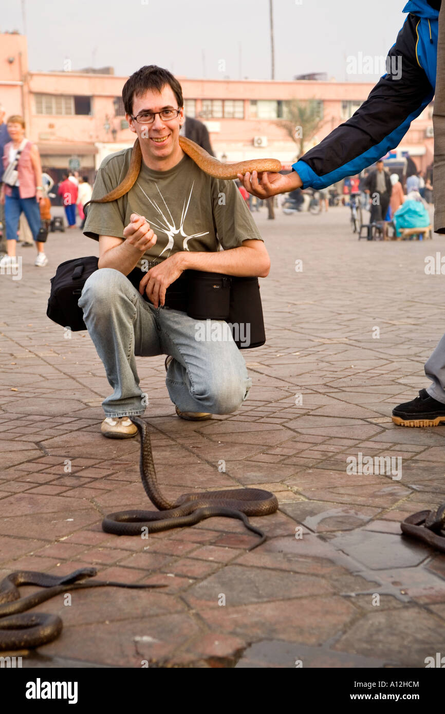 Tourist in posa con un incantatori di serpenti serpente nel Djemaa el Fna mercato in Marrakech Marocco Foto Stock