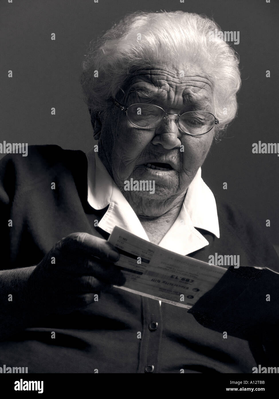 Scioccato donna anziana legge lettera o pagamento fattura contenente le cattive notizie Foto Stock