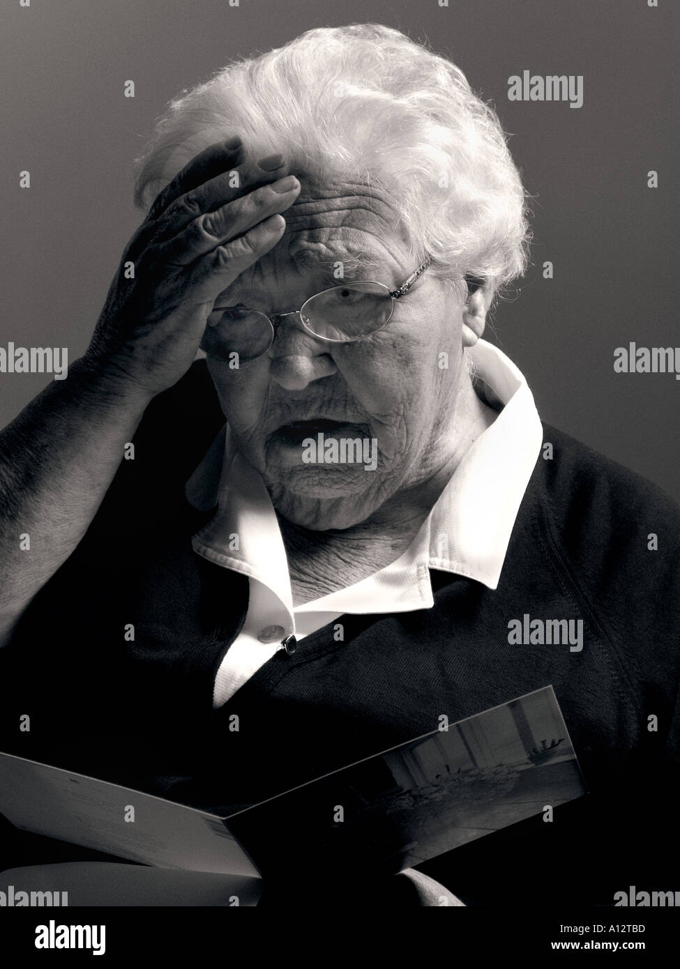 Addolorato donna anziana legge greeting card contenente le cattive notizie Foto Stock
