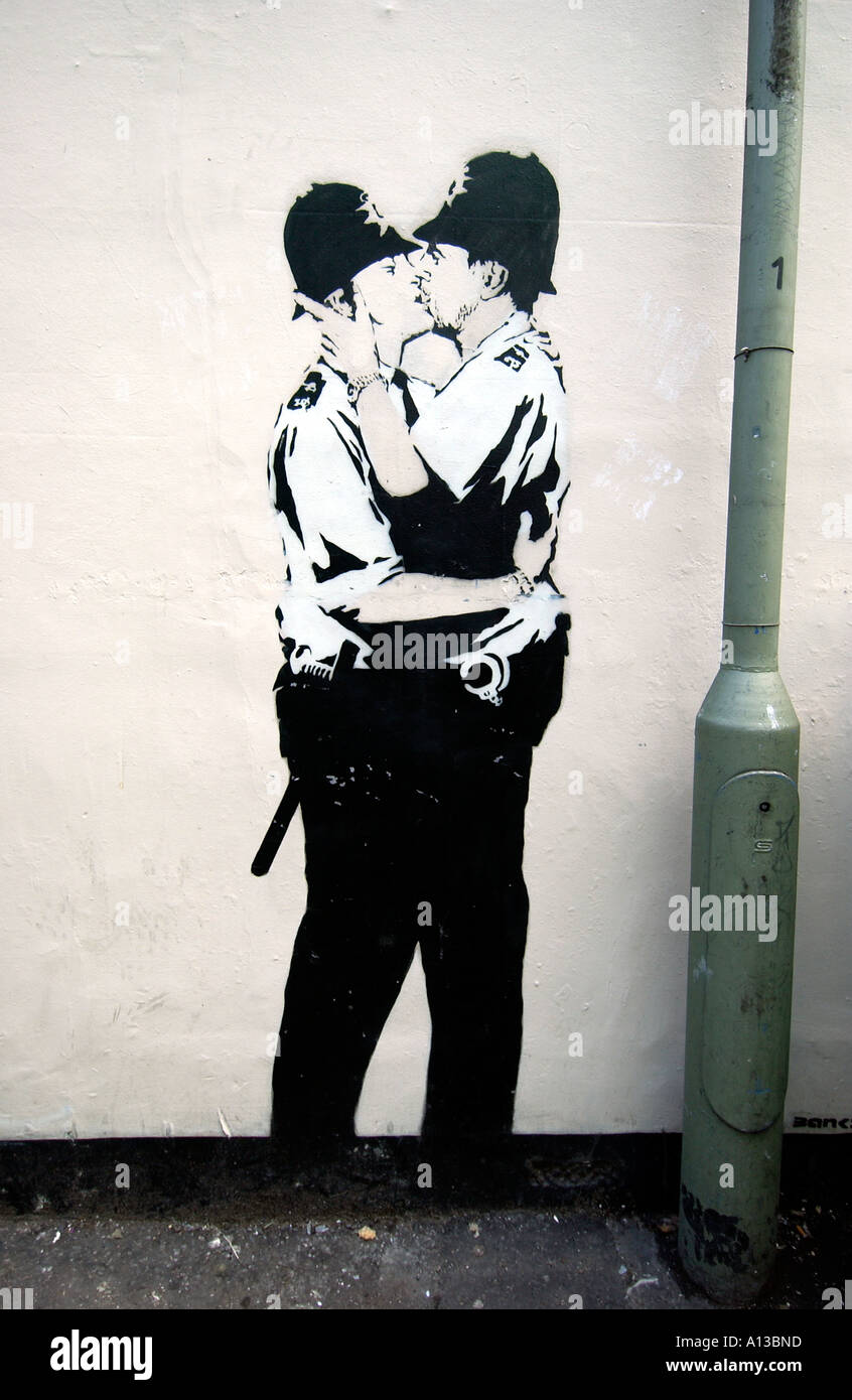 Un pezzo di stencil graffiti spruzzato di baciare due poliziotti Gay da Banksy spruzzata su una parete in Brighton, Sussex. Foto Stock
