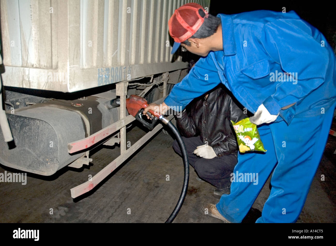 Un lavoratore il riempimento di un carrello serbatoio carburante a SINOPEC PETROL station in Kunming, in Cina. Foto Stock