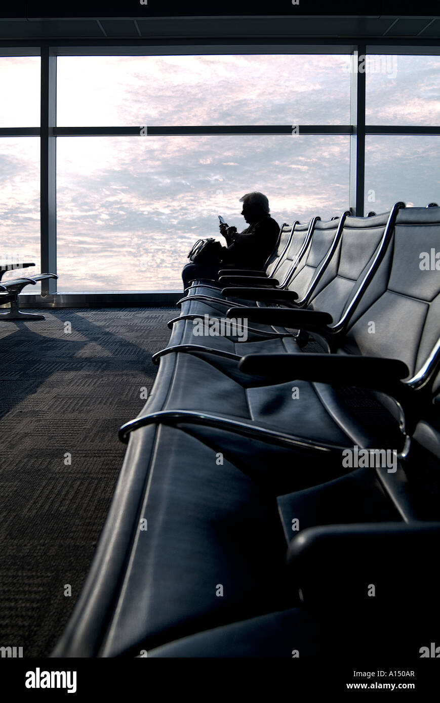 Business man in aeroporto in attesa di un telefono per la messaggistica di testo alla fine di un lungo viaggio , Filadelfia Pennsylvania USA Foto Stock