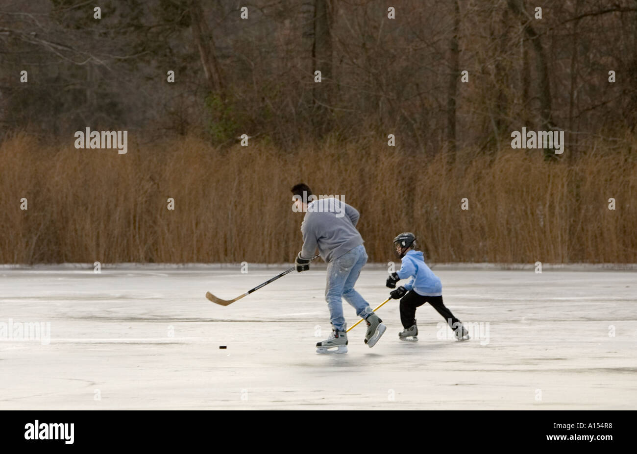 Padre e figlio giocare hockey su ghiaccio su un laghetto Foto Stock
