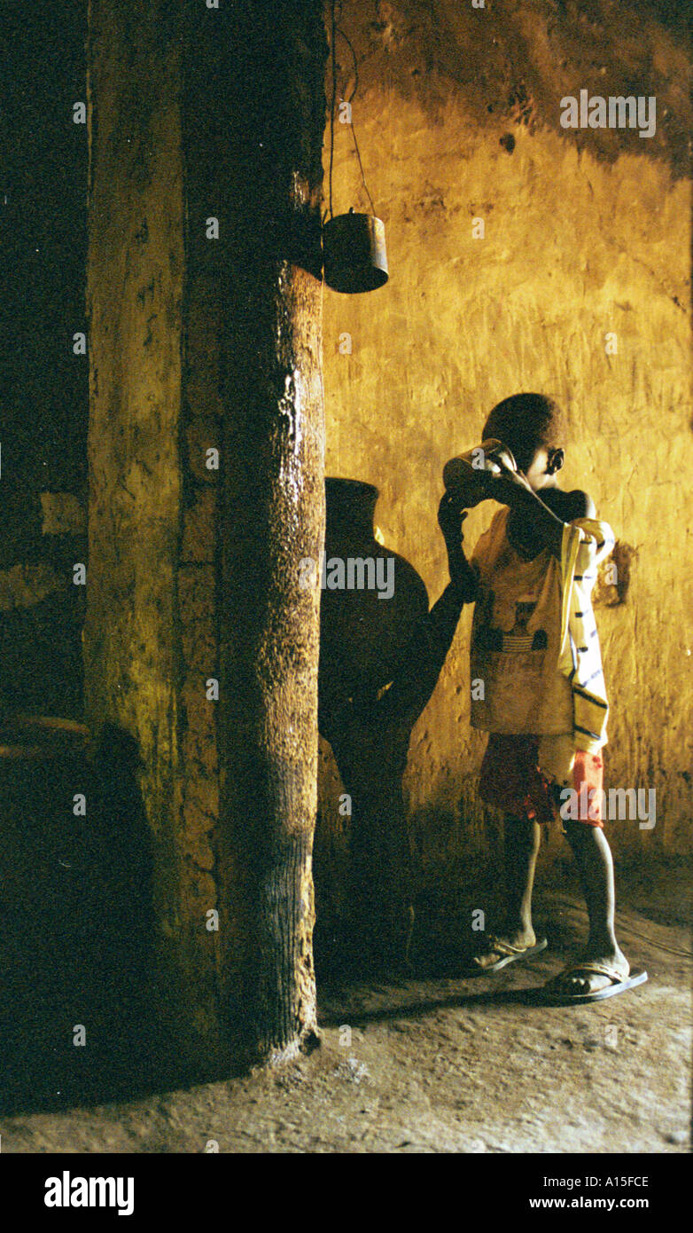 Un bambino beve acqua all'interno di una delle capanne nel villaggio di Dembel Jumpora che si trova in Africa occidentale del paese Foto Stock