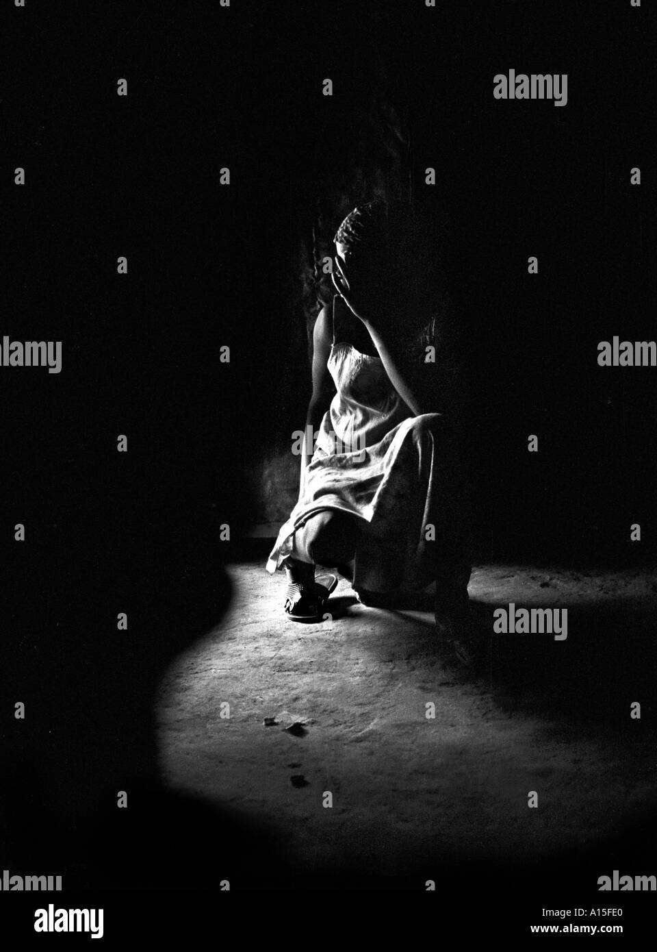 Una giovane ragazza adolescente si appoggia all'interno di una capanna di fango prima che venga portato fuori per una cerimonia di circoncisione nel villaggio di Dembel Foto Stock