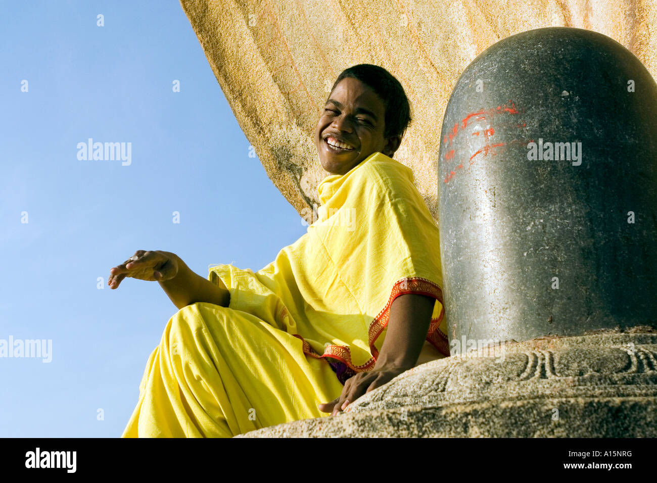 Brahmacharya giovane ragazzo indiano ridere seduto accanto a shiva lingam al tempio Veerabhadra, Lepakshi, Andhra Pradesh, India del Sud Foto Stock