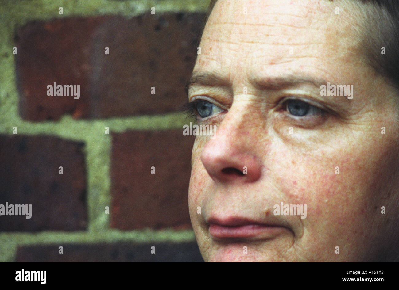 Close up della donna s faccia di fronte a un muro di mattoni Foto Stock