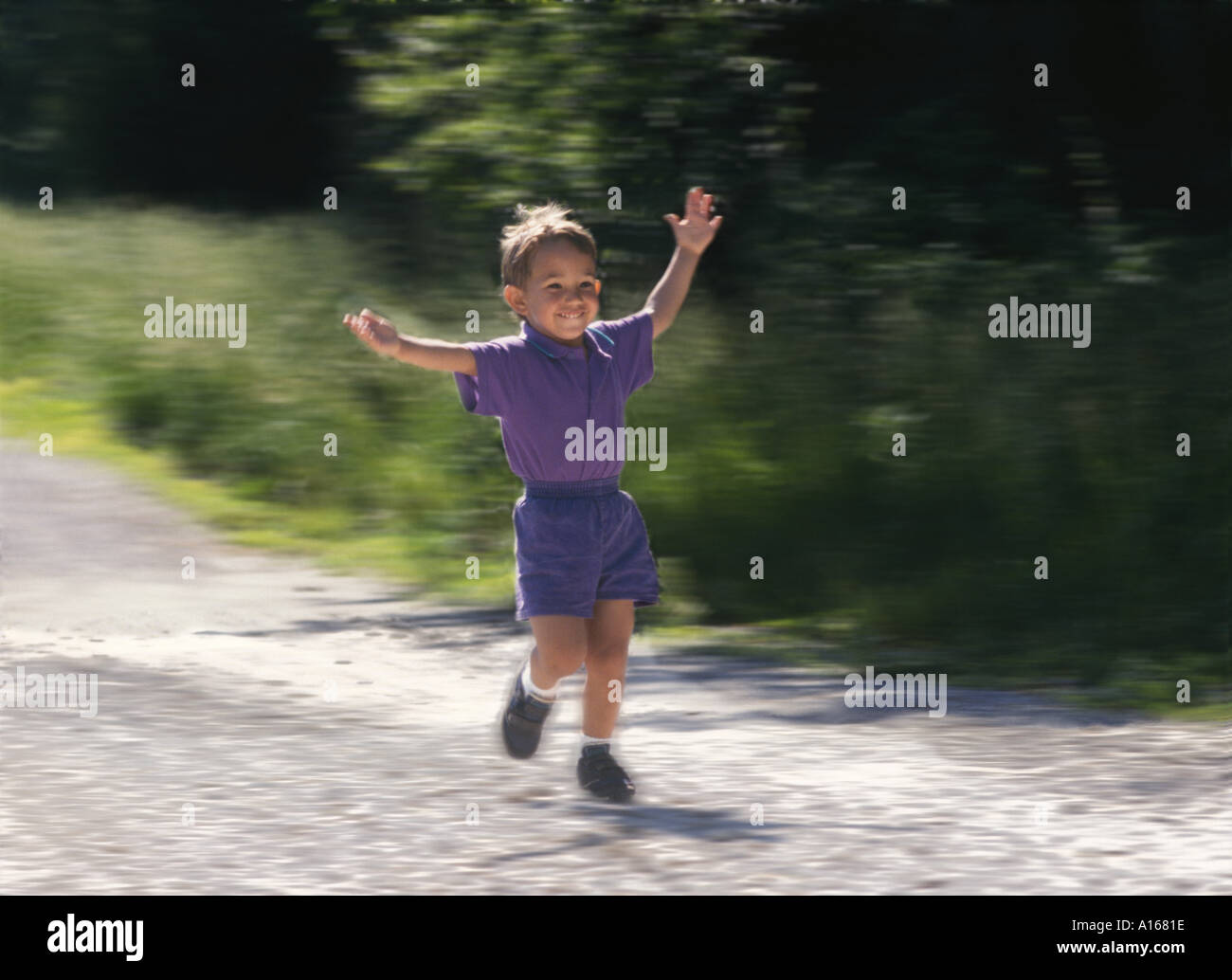 Giovane ragazzo Afghan-American, 4 anni, corre con gioia su una strada di ghiaia con le braccia spalancate in saluto in un giorno di estate, Missouri, Stati Uniti d'America Foto Stock