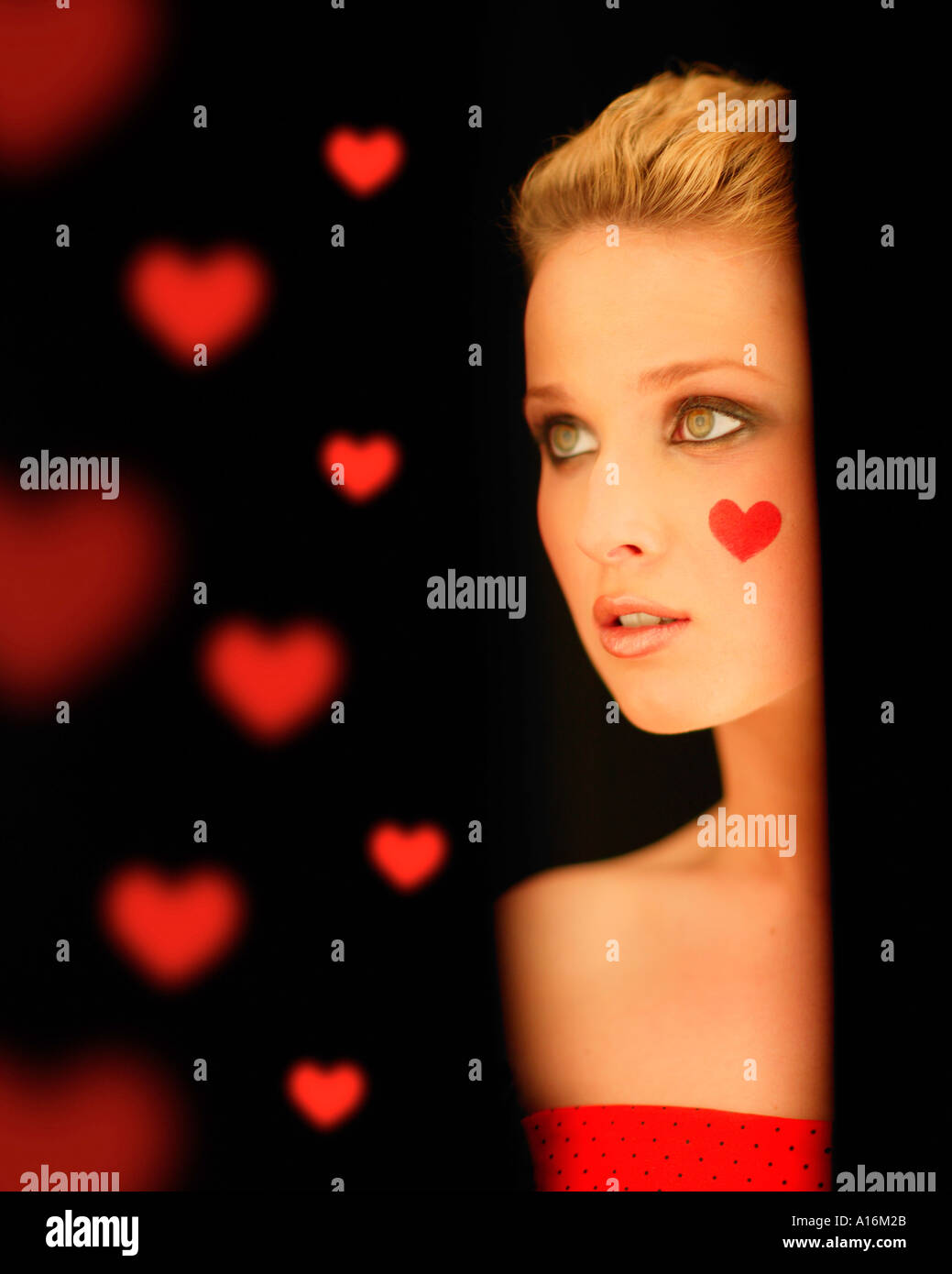 Ritratto di giovane donna 18, 19, 20, 21, 20-24, 24-29, 30-34, anni con cuore rosso dipinto sulla guancia Foto Stock
