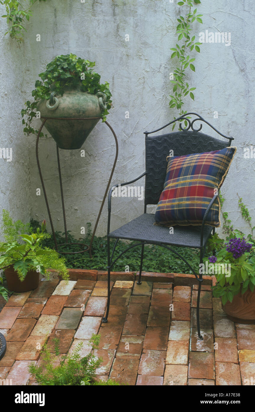Delicato sedia in ferro con tessuto colorato cuscino e un antico piantatrice in angolo privato chiuso cortile mattone Missouri negli Stati Uniti d'America Foto Stock