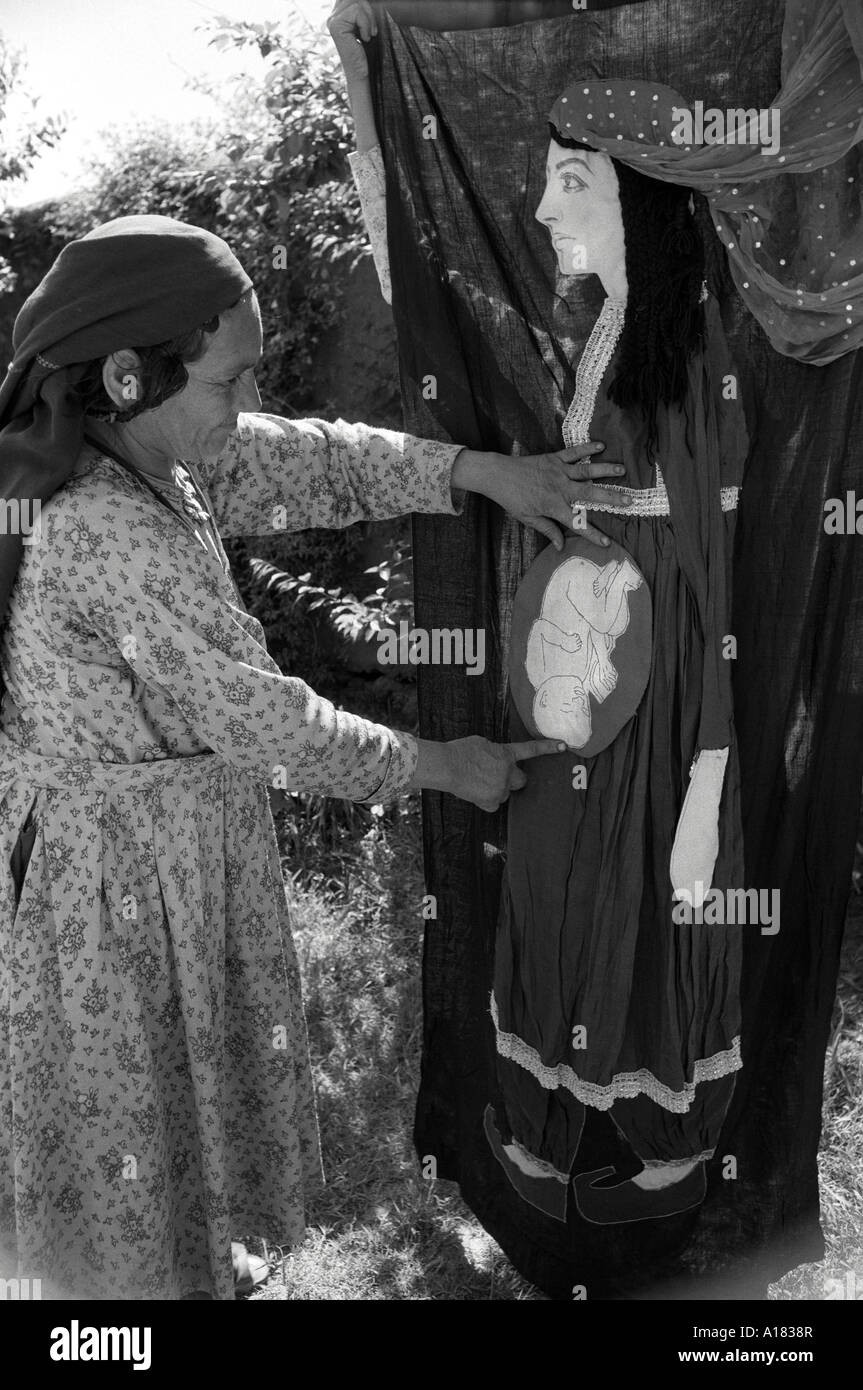 B/N di un tirocinante rurale di nascita. Posizionamento di un bambino nel grembo su una donna applicata lifsized su stoffa. Distretto di dir, N. Pakistan Foto Stock