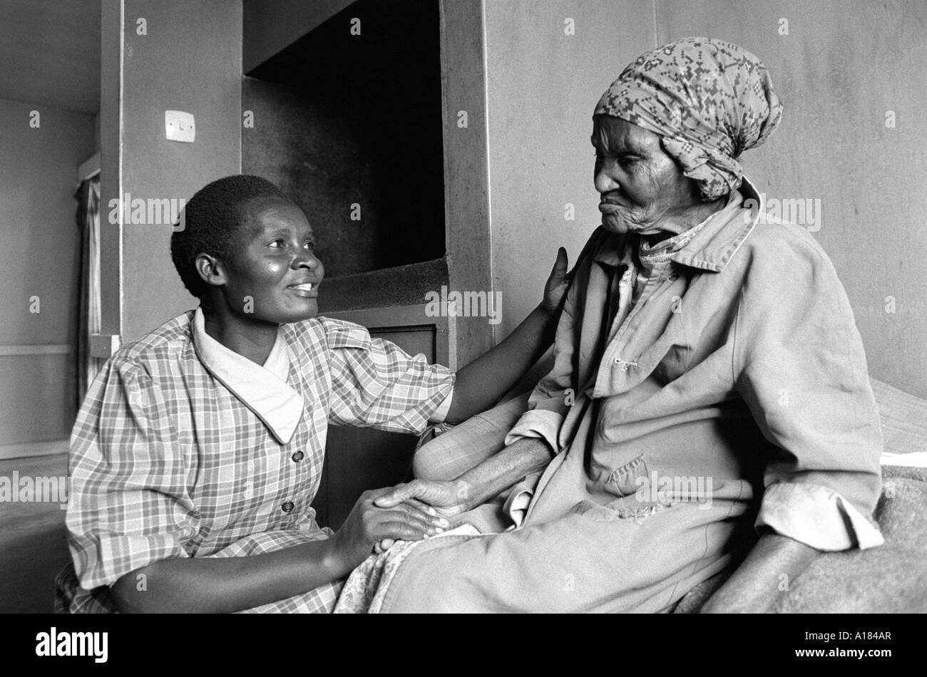 B/N di una donna che si occupa di un anziano residente in una casa di cura. Kabete, Kenya Foto Stock