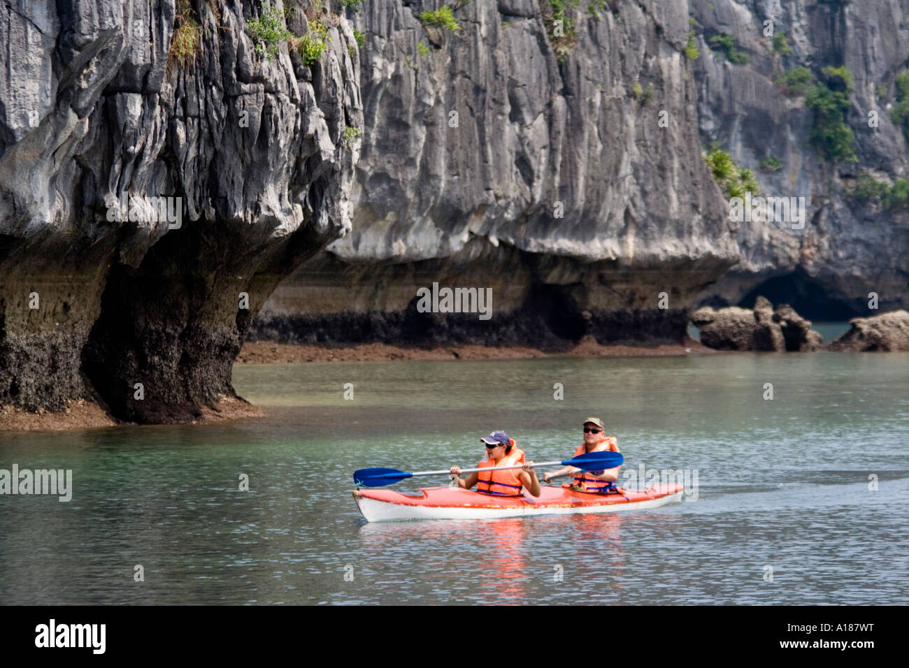 Turista giovane kayaking fuori di una baia di Halong Bay Vietnam Foto Stock