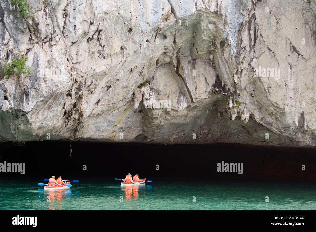 Kayaks turistico guidato in un Deap oscura grotta Tunnel Halong Bay Vietnam Foto Stock