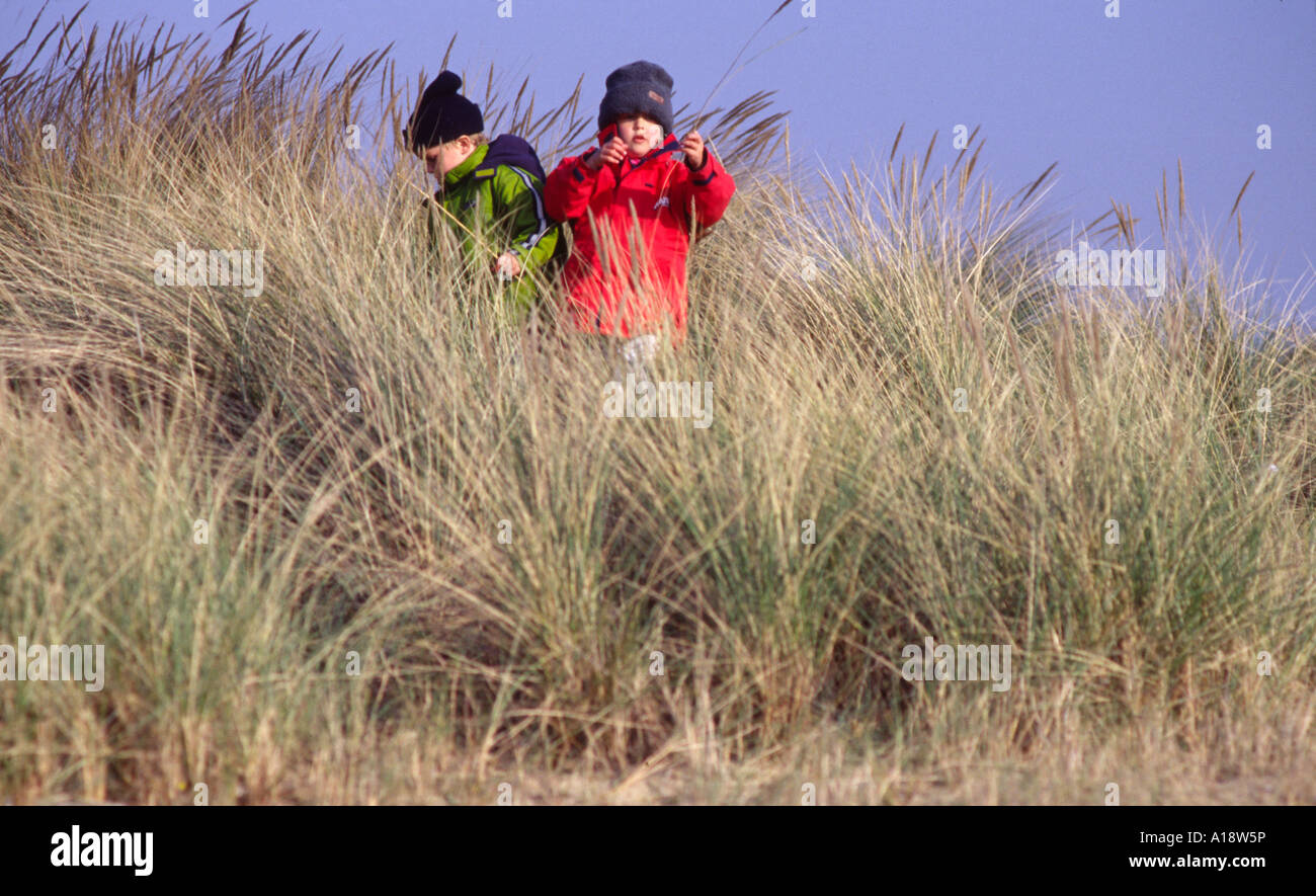 5 ragazzo e una ragazza 7 esplorando tra le dune di sabbia e di erba lunga al punto di pietra in Walton Backwaters Essex Foto Stock