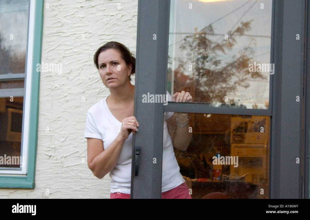 Preoccupato mom età 37 guardando fuori dalla porta sul retro. St Paul Minnesota MN USA Foto Stock