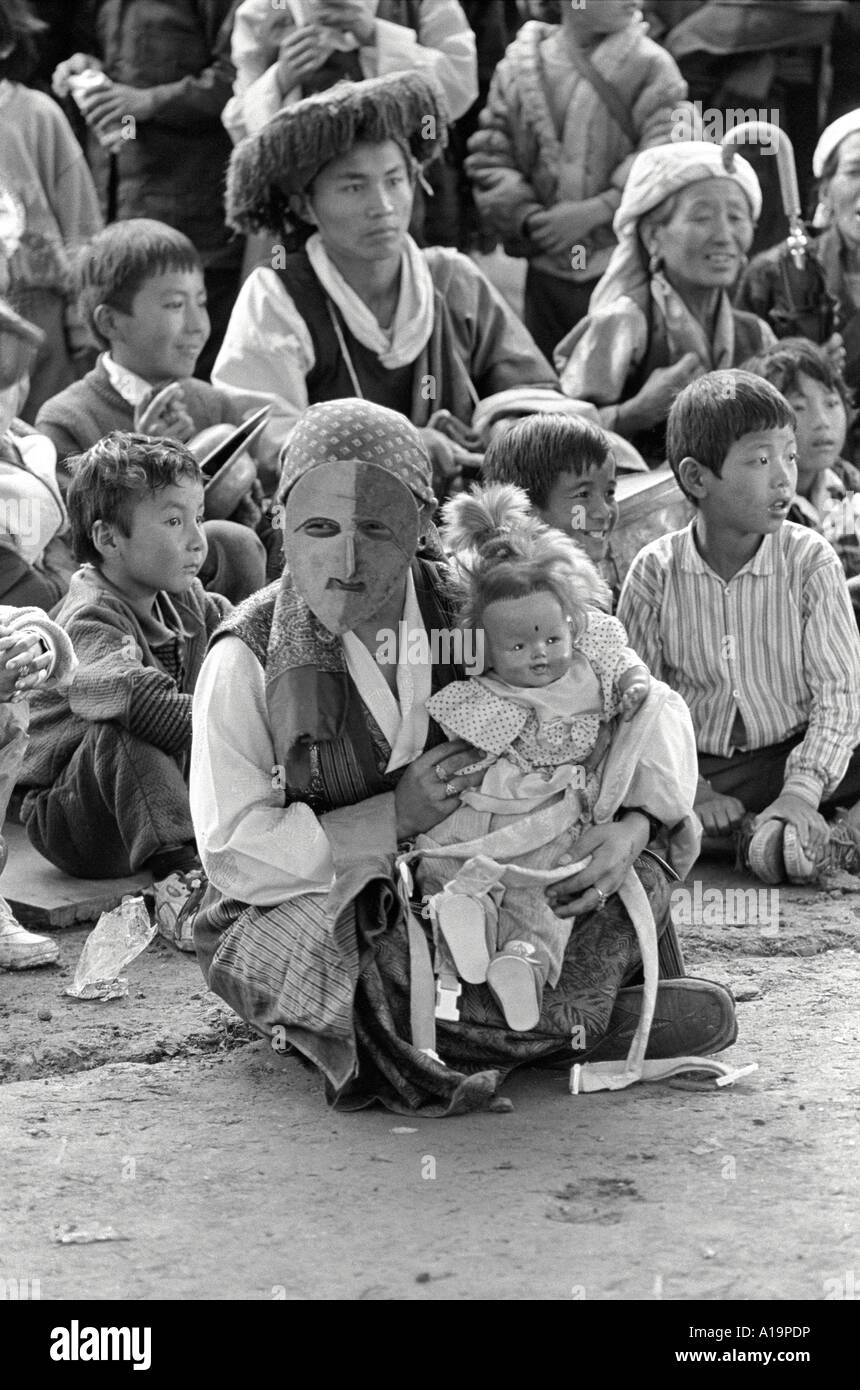 B/W dei rifugiati tibetani a Losar, il loro tradizionale festival di Capodanno. Una donna seduta indossa una maschera e tiene una bambola di dimensioni reali. Solukhumbu, Nepal Foto Stock