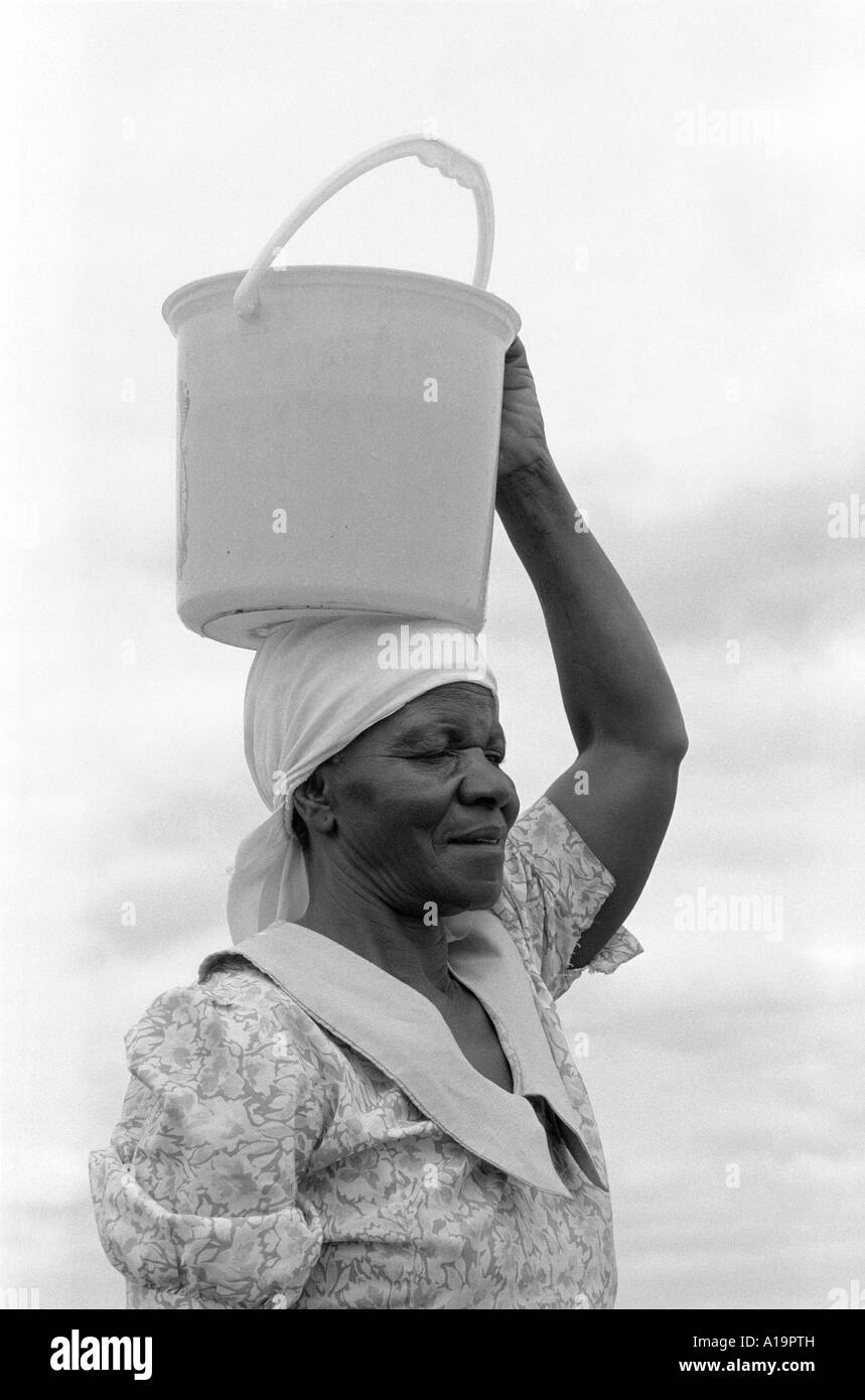 Ritratto B/N di una donna che trasporta l'acqua da una comunità bene sulla sua testa. Vicino a Gweru, Zimbabwe Foto Stock