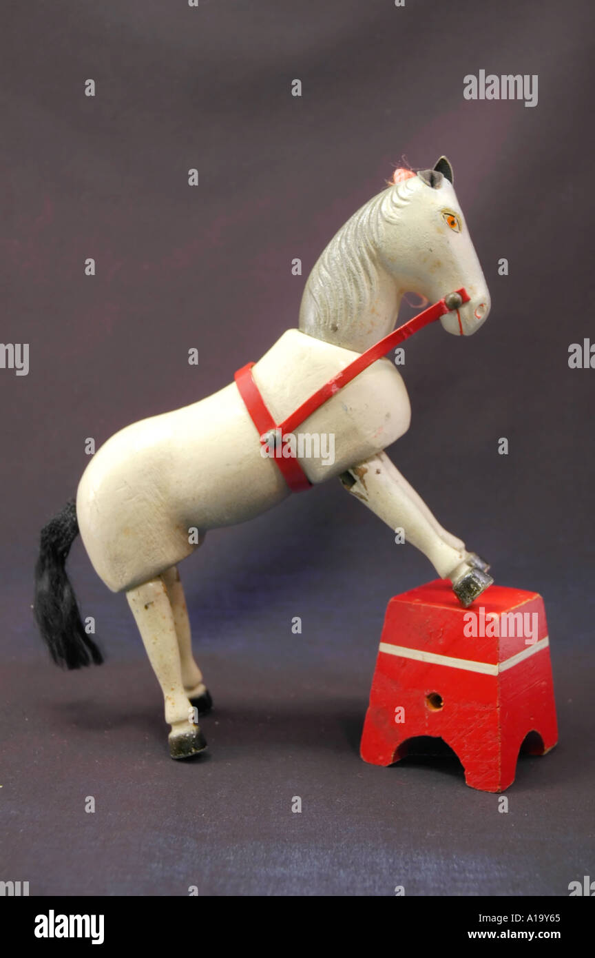 In legno antico giocattolo di circo cavallo bianco in piedi con la sua parte anteriore unghioni su uno sgabello Foto Stock